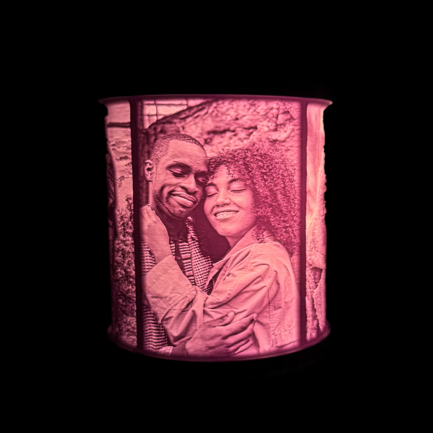Lit lithophane photo lamp showing a couple embracing, with the image glowing through the curved white shade against a dark background.