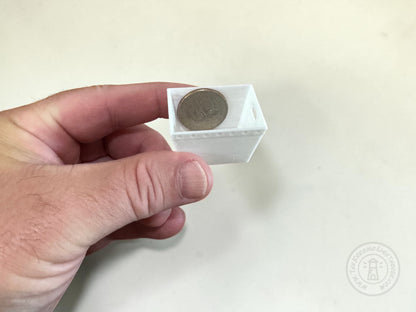 A hand holding a small white dps tray containing a coin for scale, against a plain light background.