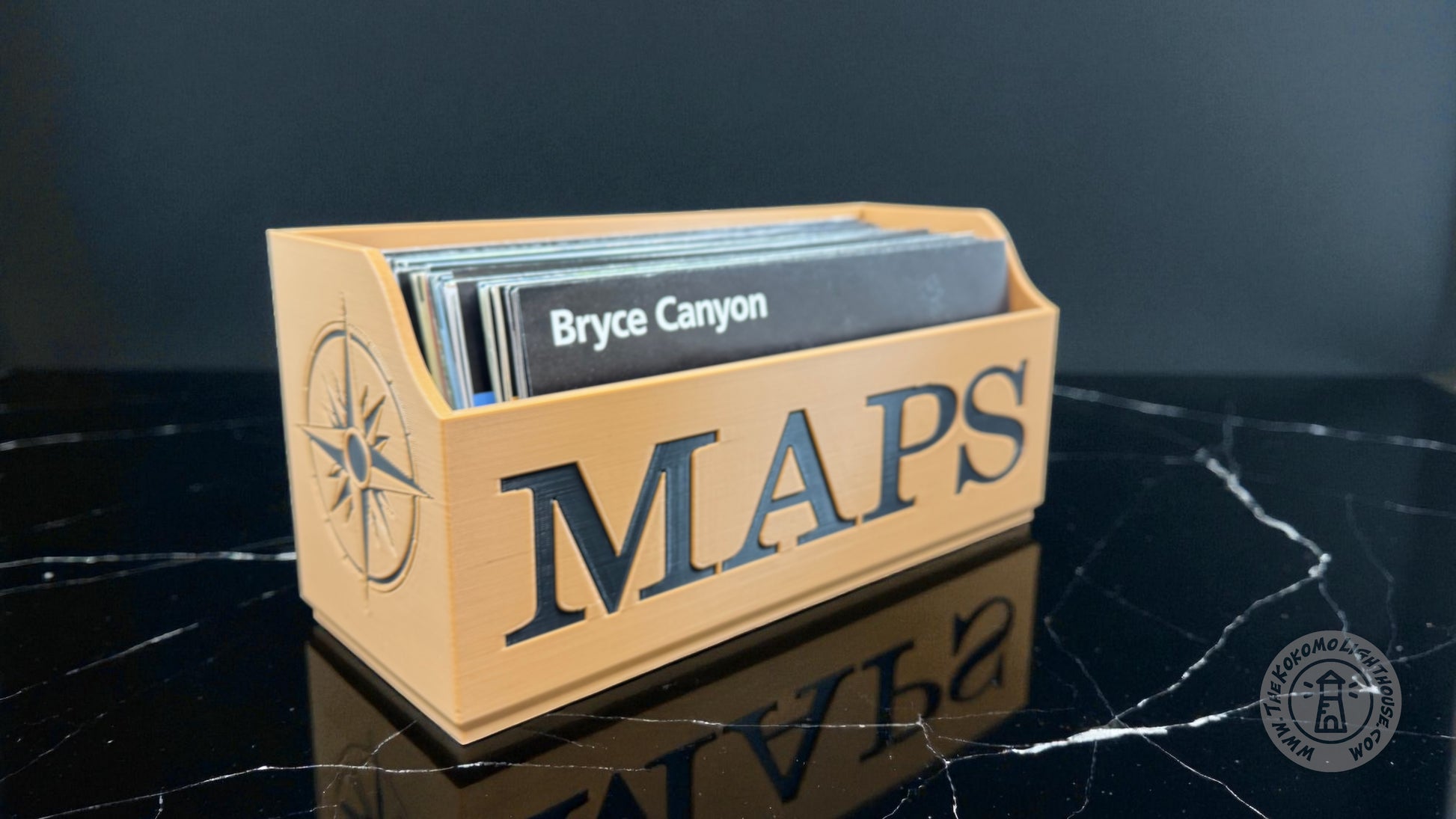 Tan Map holder with 'MAPS' black text and compass design on a dark surface