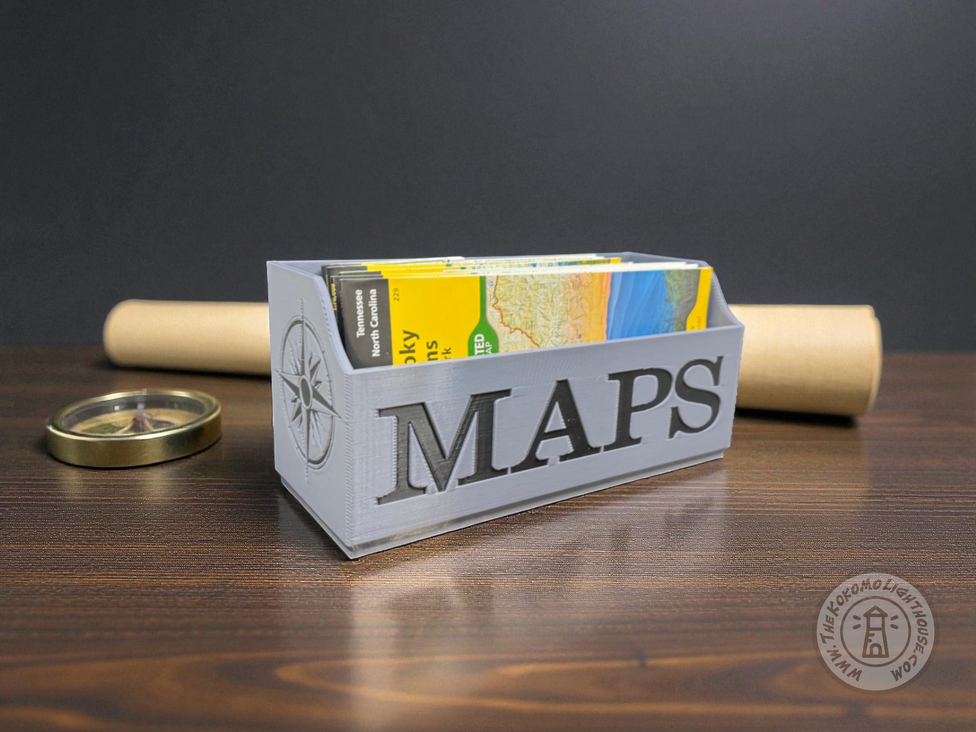 Gray Map holder with 'MAPS' in black text on a wooden surface with a dark background
