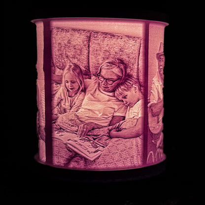 Lit family photo lithophane lamp showing a grandmother reading with two children, with the image wrapped around the white lamp shade.