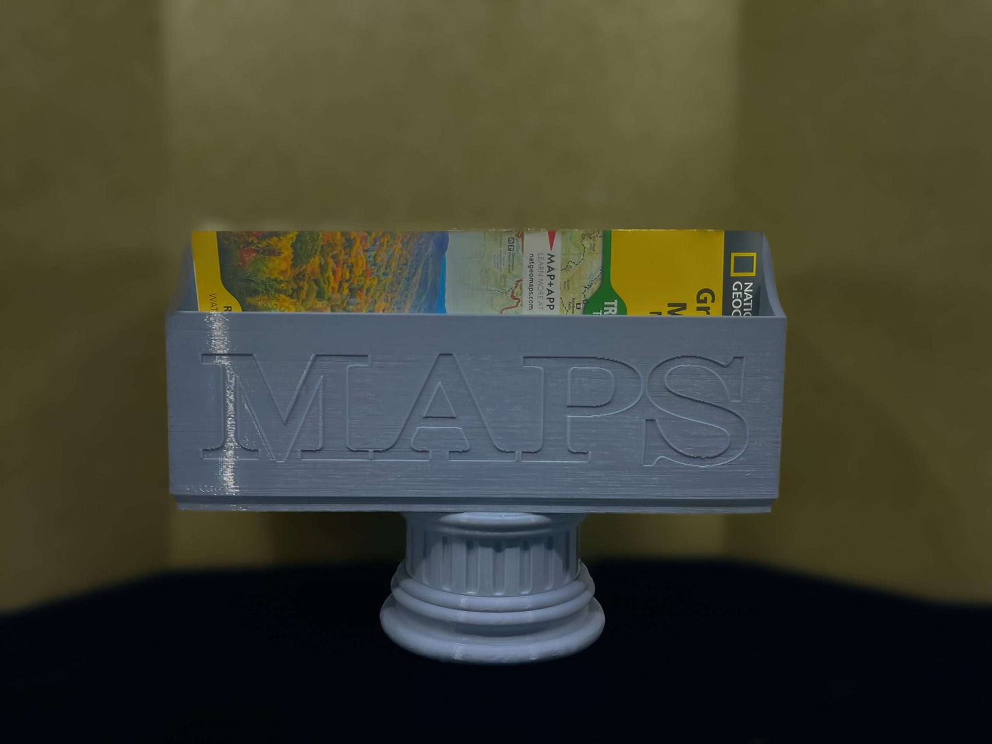 Gray NatGeo Map Box holding maps on a gray pedestal