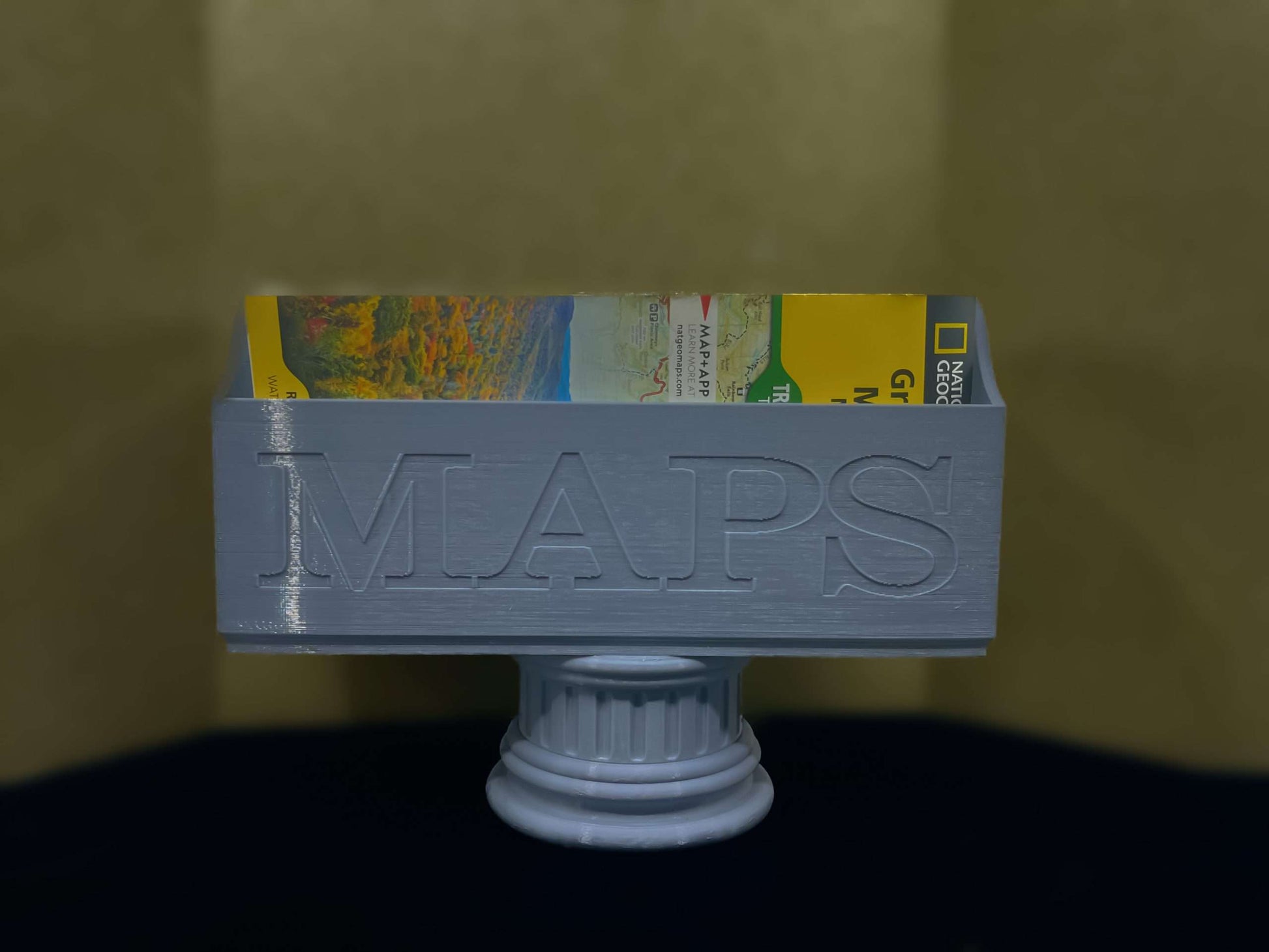 Gray NatGeo Map Box holding maps on a gray pedestal