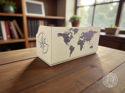 Green Map box with compass design on side and world map on back in black detail sitting on a wooden table in a library