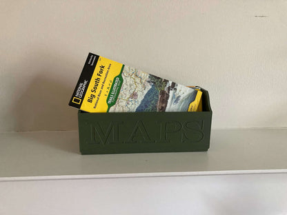 Green NatGeo Map Box holding maps on white shelf