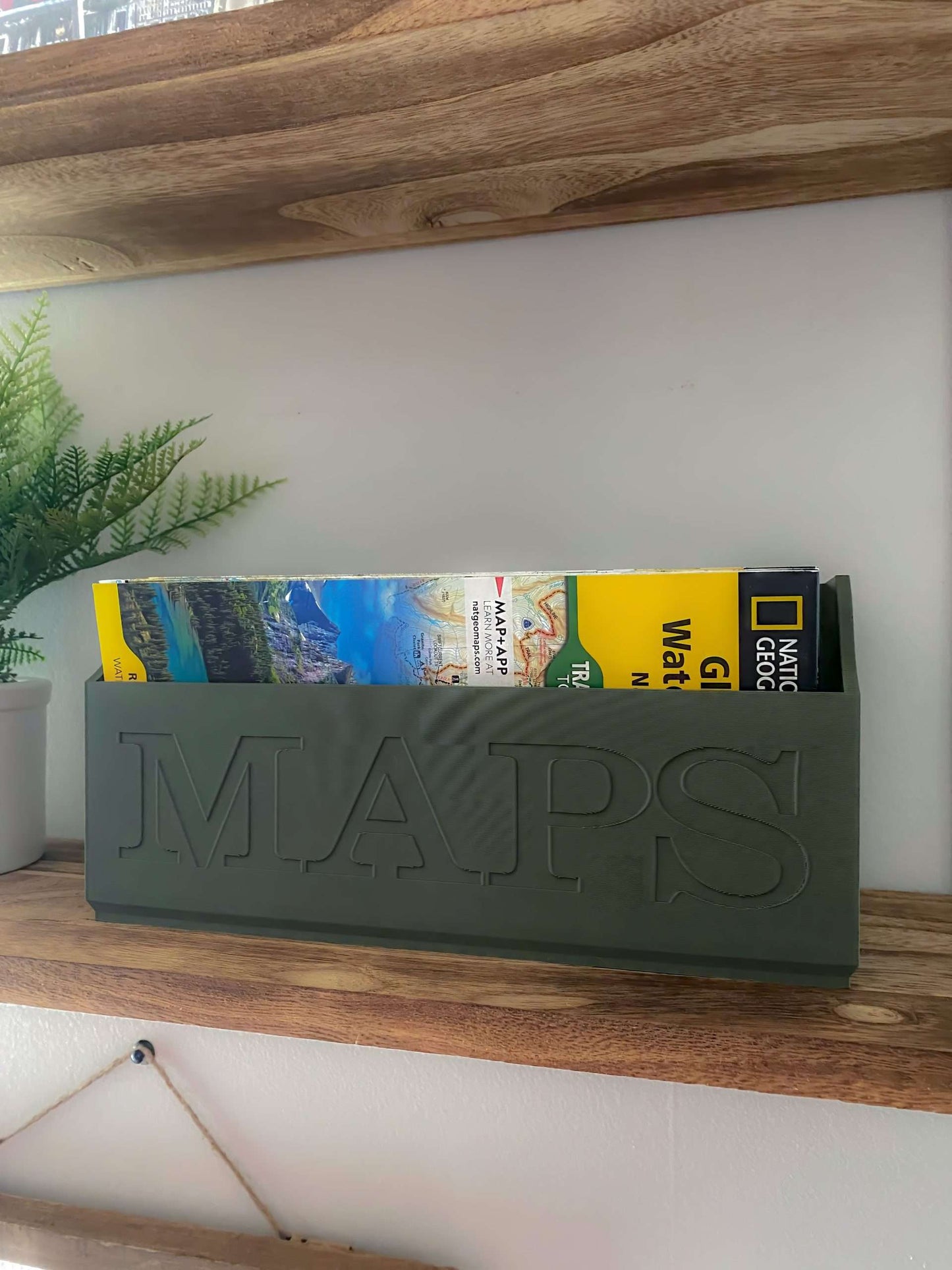 Green NatGeo Map Box holding maps on a wooden shelf
