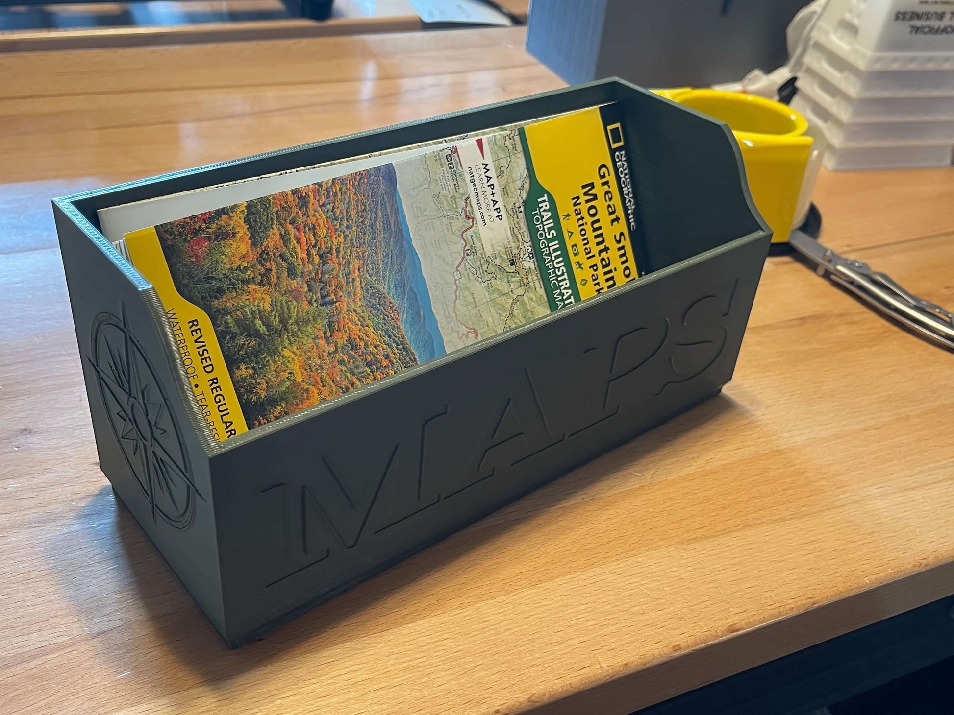 Green NatGeo Map Box holding maps on workbench