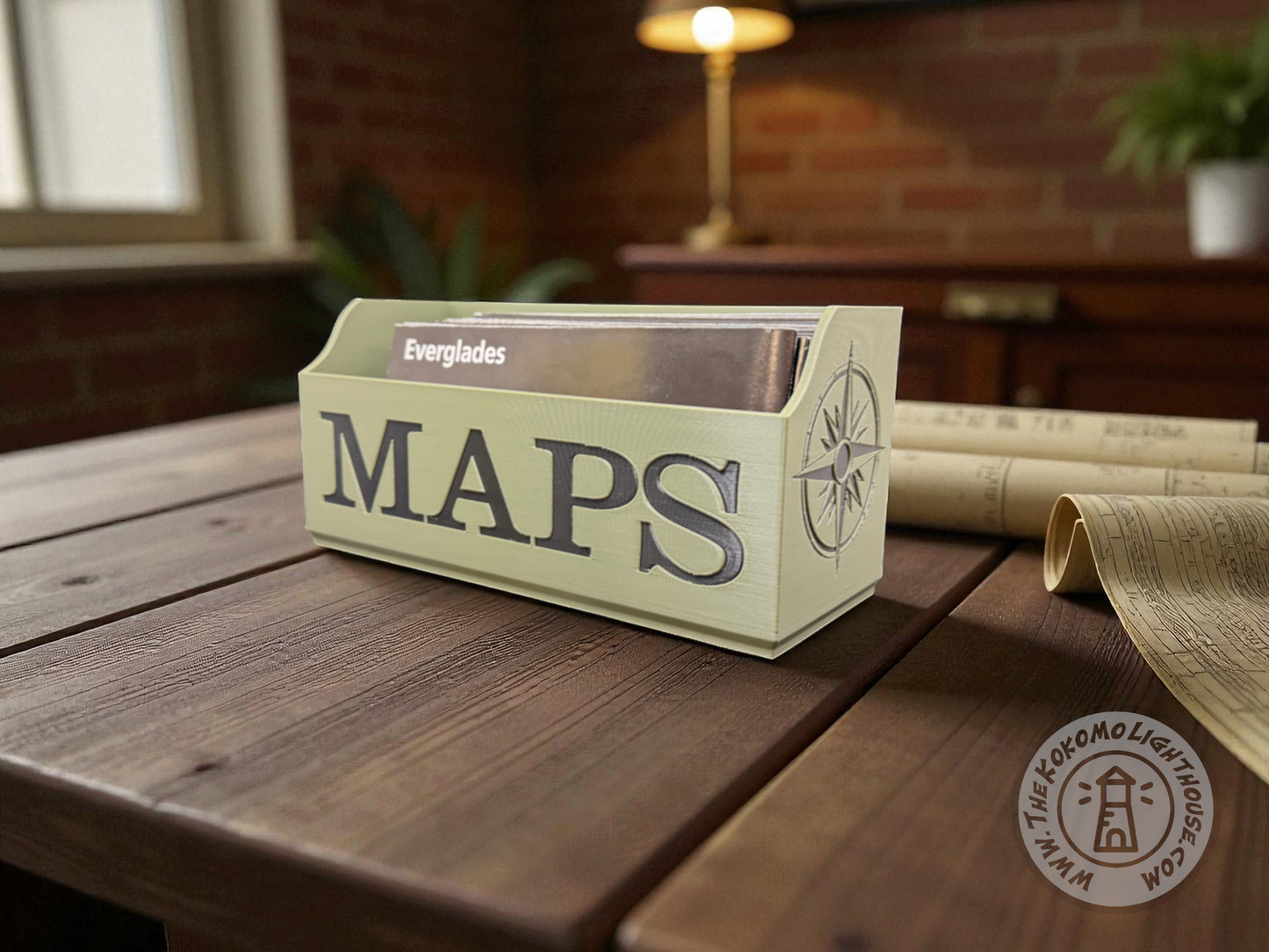 Green NatGeo map box labeled 'Maps' in black writing on a wooden table with rolled-up maps in the background.