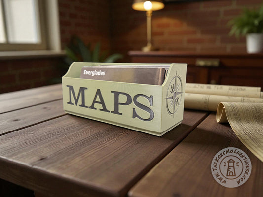 Green NatGeo map box labeled 'Maps' in black writing on a wooden table with rolled-up maps in the background.