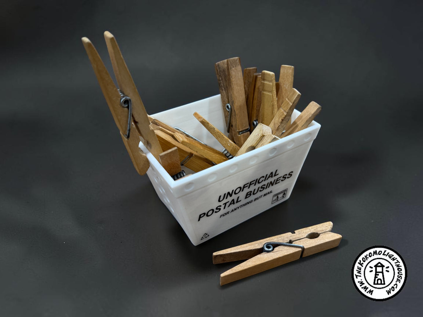 A mini postal tub filled with clothespins on a dark background