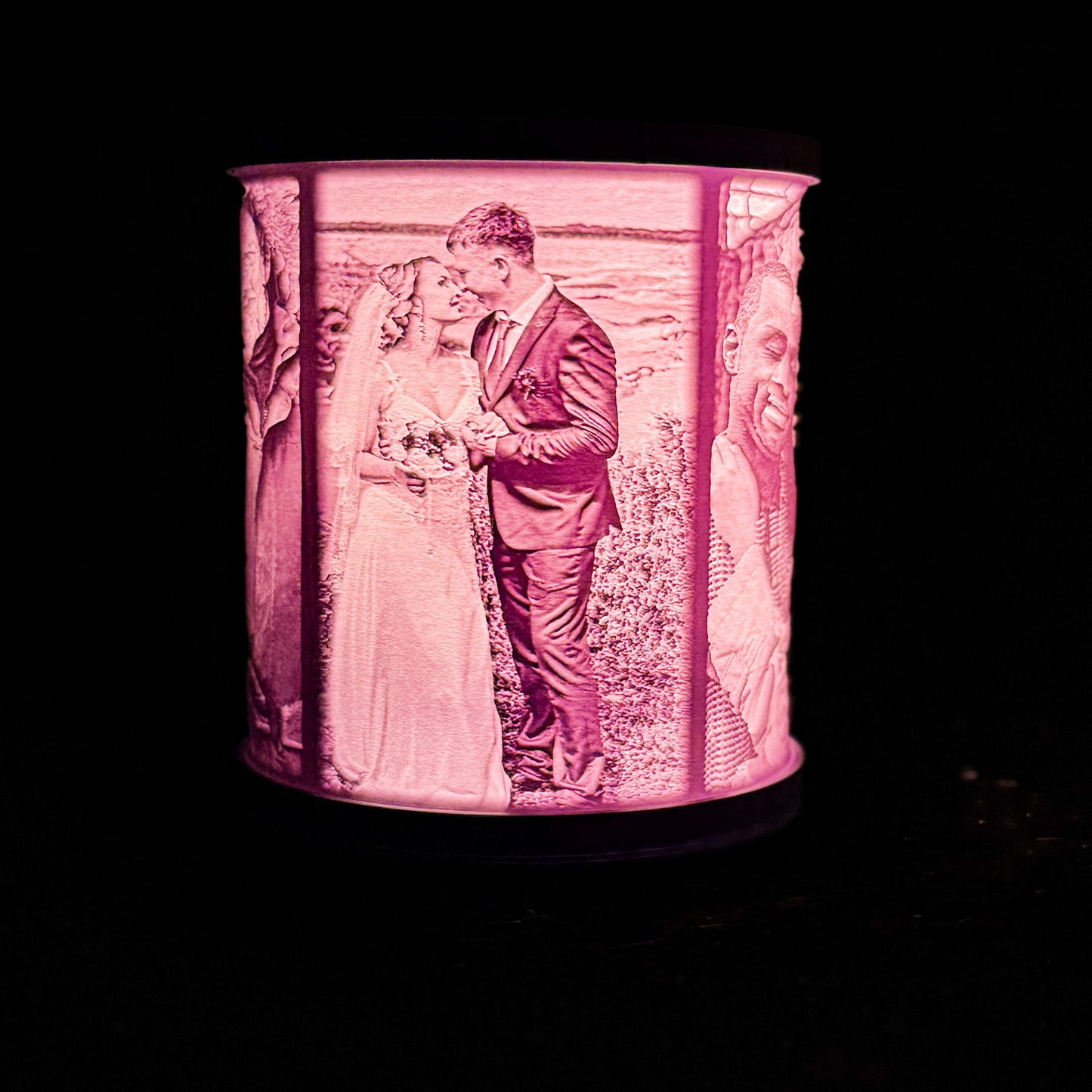 Lit wedding lithophane lamp showing a bride and groom kissing, with additional photo panels visible around the curved shade.