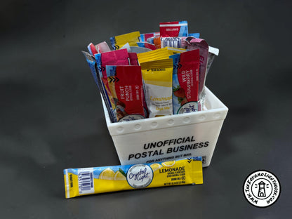 A mini postal tray filled with drink packets with one in front on a dark background