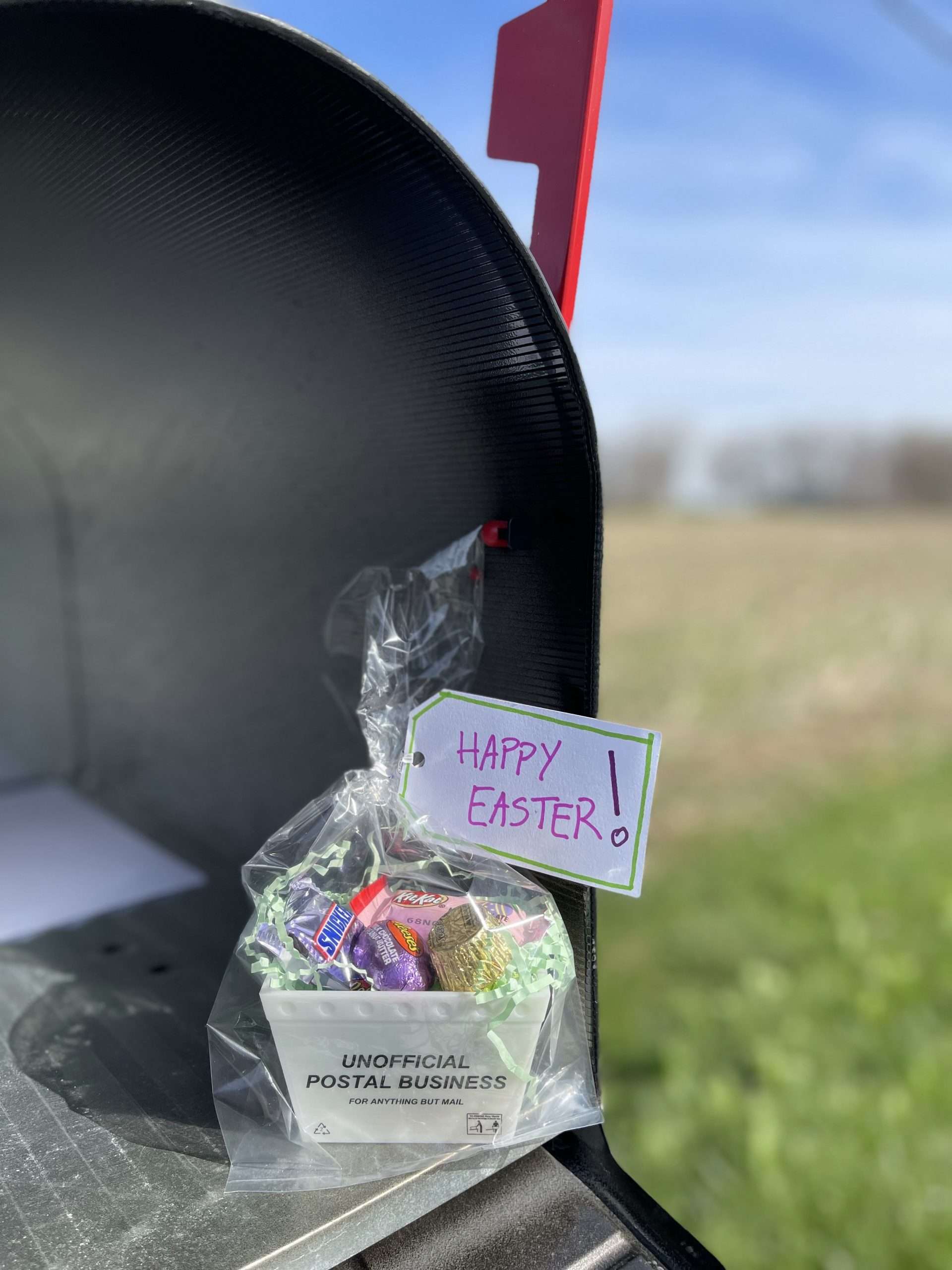 A gift basket made from a mini postal tub filled with easter candy and with a Happy Easter note